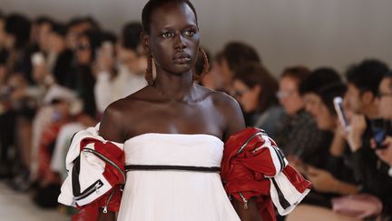 Chez Margiela, la collection, dont les références au 18e siècle et à la Révolution côtoient l'univers de la pêche et des oiseaux, exprime tout le foisonnement créatif de John Galliano. Costumes historiques et garde-robe fonctionnelle se mêlent dans une fantaisie poétique, un bustier en toile de Jouy se greffe sur une robe argentée aux airs de combinaison spatiale. Les cuissardes sont de sortie et les Tabi boots, ces bottines emblématiques de la maison d'inspiration japonaise où le gros orteil est séparé des autres, deviennent elles aussi des cuissardes.Les contrastes sont omniprésents. Les oiseaux s'invitent sous forme de grands imprimés colorés sur une robe drapée en satin ou de morceaux de celluloïd appliqués sur une jupe en plaid, tandis que leurs plumes accessoirisent les coiffures.
 (FRANCOIS GUILLOT / AFP)