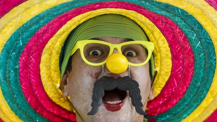 Une balle de ping-pong, une moustache en plastique et un chapeau bariol&eacute;, &ccedil;a vous change un supporter br&eacute;silien, le 17 juin &agrave; Sao Paulo.&nbsp; (MIGUEL SCHINCARIOL / AFP)