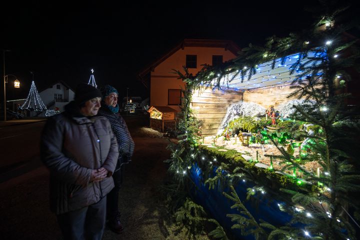 Des visiteurs en train d'admirer une mise en scène de la Nativité, dans le village de Banovci. (JURE MAKOVEC / AFP)