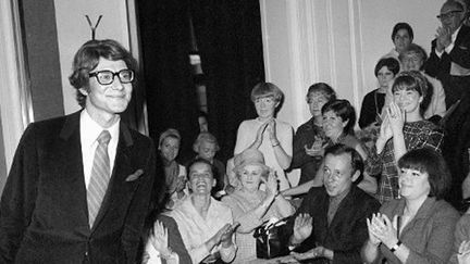 Yves Saint Laurent saluant l'assistance à l'issue du 10e défilé de sa propre maison de couture, le 4 août 1966 à Paris.
 (Archives AFP)