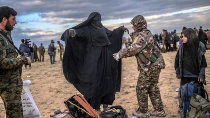 Une Kurde, membre des Forces démocratiques syriennes, fouille une femme qui a quitté le camp de l'organisation Etat islamique à Baghouz (Syrie), le 27 février 2019. (BULENT KILIC / AFP)