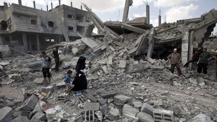 4 août : une Palestinienne avec ses enfants traverse des ruines dans le camp de Rafah. (MAHMUD HAMS / AFP)