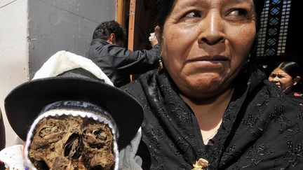 Une Bolivienne pose &agrave; c&ocirc;t&eacute; d'une "natita" (nom affectueux pour "cr&acirc;ne humain") &agrave; La Paz, lors d'une c&eacute;r&eacute;monie traditionnelle consacr&eacute;e &agrave; la mort, le 8 janvier 2011. (AIZAR RALDES / AFP)