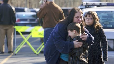 Une femme r&eacute;conforte un petit gar&ccedil;on devant l'&eacute;cole primaire de Newtown (Connecticut) o&ugrave; une fusillade a &eacute;clat&eacute;, le 14 d&eacute;cembre 2012.&nbsp;&nbsp; (MICHELLE MC LOUGHLIN / REUTERS )