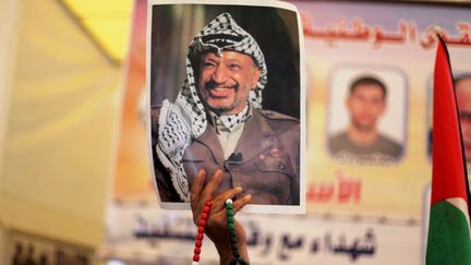 Une photo de&nbsp;Yasser Arafat, l'ancien pr&eacute;sident de l'Autorit&eacute; palestinienne, brandie par un Palestinien pour comm&eacute;morer les 10 ans de sa mort, le 10 novembre 2014 &agrave; Gaza. (ASHRAF AMRA / ANADOLU AGENCY / AFP)