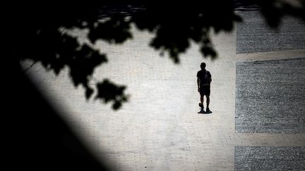 Un homme marche sur les berges de la Garonne, à Toulouse, en plein épisode de canicule, le 17 mai 2022. (LIONEL BONAVENTURE / AFP)