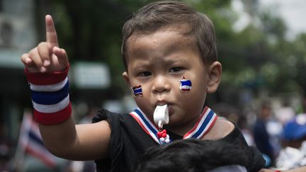 Un enfant est assis sur les &eacute;paules d'un manifestant antigouvernement, dans un rassemblement &agrave; Bangkok (Tha&iuml;lande), le 2 avril 2014. (NICOLAS ASFOURI / AFP)