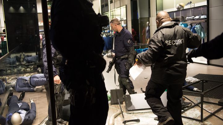 Des policiers s&eacute;curisent un magasin des Champs-&Eacute;lys&eacute;es, vandalis&eacute; par des casseurs, le 12 mai 2013. (BERTRAND LANGLOIS / AFP)