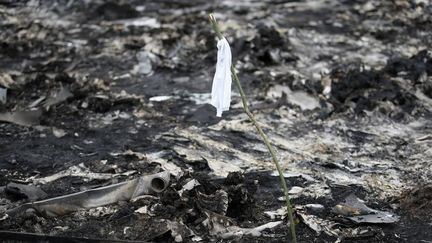 Un drapeau blanc est plac&eacute; par les services d'urgence ukrainiens pour signaler la pr&eacute;sence d'un corps au milieu des d&eacute;bris. (MAXIM ZMEYEV / REUTERS)