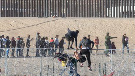 Deux hommes escaladent un grillage installé à la frontière entre le Mexique et le Texas (Etats-Unis), le 15 mars 2024. (DAVID PEINADO / ANADOLU / AFP)