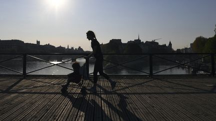 Une femme tente de combiner promenade en poussette et activité sportive sur le Pont des Arts à Paris, en avril 2020. (ALAIN JOCARD / AFP)