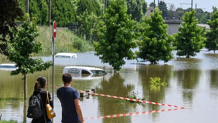 Des passants regardent les dégâts causés par les intempéries, à Louhans (Saône-et-Loire) le 17 juillet 2021. (PHILIPPE DESMAZES / AFP)