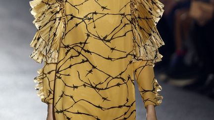 Les premières silhouettes paraissent sages et même austères, avec des jupes qui arrivent sous le genou, des coupes assez larges, chez Dries Van Noten. Mais très vite apparaît de la légèreté, avec du doré venu réveiller du beige, comme si des feuilles d'or étaient collées sur les vêtements. Puis les volants se font de plus en plus nombreux avec des plissages. Le créateur belge excelle dans les imprimés : de grandes fleurs colorées égayent des vestes noires, des motifs ethniques se déploient, des brillants apparaissent. Il a imaginé cette garde-robe "pour une femme de 2014, mais une femme forte, comme Loulou de la Falaise". 
 (JOEL SAGET / AFP)