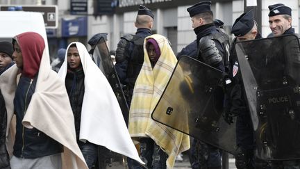 Des policiers encadrent des migrants au cours de l'&eacute;vacuation du campement de Stalingrad, vendredi 4 novembre 2016 &agrave; Paris. (PHILIPPE LOPEZ / AFP)