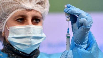 Une femme membre du personnel soignant préapre une injection de vaccin contre le Covid-19 à partir d'un flacon d'AstraZeneca, le 16 mars 2021 à Kiev (Ukraine). (SERGEI SUPINSKY / AFP)