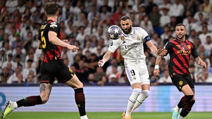 Le capitaine du Real Madrid, Karim Benzema, bien entouré par les défenseurs de Manchester City, John Stones et Kyle Walker, à l'occasion de la demi-finale aller de Ligue des champions, le 9 mai 2023, au stade Santiago Bernabeu. (JAVIER SORIANO / AFP)