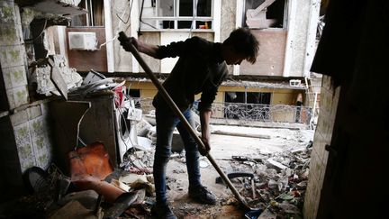 Un jeune garçon nettoie une maison détruite dans la ville assiégiée de Douma, dans la Ghouta orientale, le 25 février 2018.&nbsp; (BASSAM KHABIEH / REUTERS)