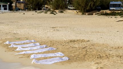 Corps de sable recouverts d'un linge blanc sur la plage de Lampedusa: une performance de l'artiste tunisienne Sadika Keskes. Comme les corps de migrants noyés, rejetés par la Méditerranée sur l'île italienne...   (Clara Puente)