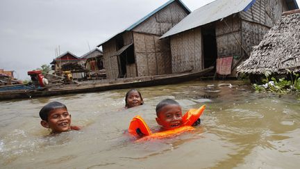 Des enfants nagent devant leur maison inond&eacute;e &agrave; Kandal (Cambodge), le 7 octobre 2013. (PRING SAMRANG / REUTERS)