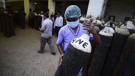 Un soignant transporte une bouteille d'oxygène à&nbsp;Allahabad en Inde, le 20 avril 2021. Les hôpitaux sont confrontés à une pénurie d'oxygène. (SANJAY KANOJIA / AFP)