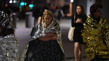 Des personnes&nbsp;abritées sous des couvertures de survie quittent le quartier du London Bridge après l'attaque, le 3 juin 2017 à Londres (Royaume-Uni). (CHRIS J RATCLIFFE / AFP)