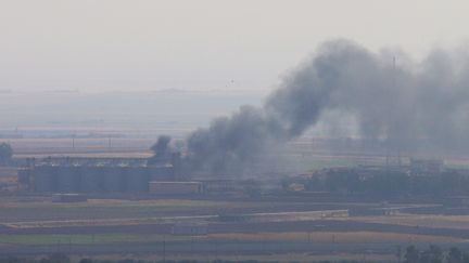 De la fumée s'échappe de bâtiments près de la ville de Ras Al-Aïn, le 18 octobre 2019, en Syrie. (STOYAN NENOV / REUTERS)