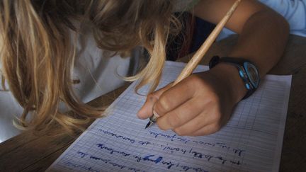 Une élève de CM2 écrit une dictée dans une école primaire de Caen (Calvados), le 8 juin 2007. (MYCHELE DANIAU / AFP)