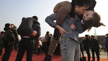 Des couples tentent de battre le record du baiser le plus long entre un homme et la femme qu'il doit porter &agrave; Hefei (Chine), le 18 f&eacute;vrier 2012. (REUTERS)