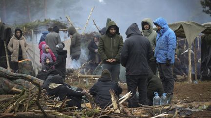 Un groupe de migrants se tient dans un camp près de la frontière biélorusse-polonaise, dans la région de Grodno, le 14 novembre 2021. (OKSANA MANCHUK / BELTA / AFP)