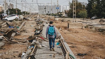 Un homme marche sur une voie ferrée à Sedavi, dans la banlieue sud de Valence, le 31 octobre 2024. (BORJA ABARGUES / ANADOLU / AFP)