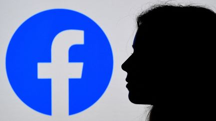 Une personne photographiée devant le logo du réseau social Facebook, le 17 août 2021. (OLIVIER DOULIERY / AFP)