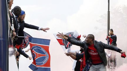 Des joueurs du Paris Saint-Germain saluent leurs supporters lors d'une parade en bus dans les rues de Paris, le 13 mai 2013. (KENZO TRIBOUILLARD / AFP)