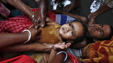 Un Hindou touche une petite fille avec son pied lors d'un rituel religieux pendant le festival Gajan &agrave; Kolkata (Inde), le 13 avril 2014. (RUPAK DE CHOWDHURI / REUTERS)