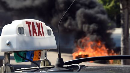 Des chauffeurs de taxi br&ucirc;lent des pneus en marge d'une manifestation &agrave; Marseille (Bouches-du-Rh&ocirc;ne), jeudi 25 juin 2015. (ANNE-CHRISTINE POUJOULAT / AFP)