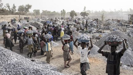 Arrivées au sommet, des dizaines de personnes dont beaucoup de femmes, certaines avec un bébé au dos, apportent alors aux acheteurs leurs bassines remplies de granite.&nbsp; &nbsp; (JOHN WESSELS / AFP)