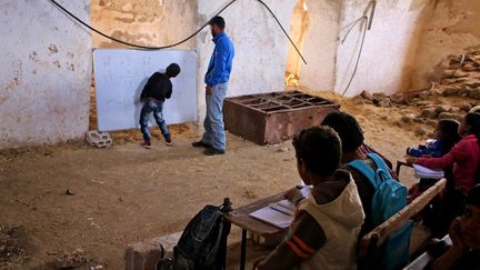 c'est mieux que rien. Ces enfants suivent un cours d'arithmétique dispensé avec les moyens du bord, dans une école de fortune. Venus de zones pro-gouvernementales, ils se trouvent actuellement dans la région de Deraa tenue par les rebelles. Cette «salle de classe» peu académique met un semblant de normalité dans la vie chaotique de ces enfants déplacés.
 (MOHAMAD ABAZEED / AFP - Novembre 2016)