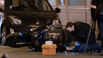 Des policiers examinent un v&eacute;hicule retrouv&eacute; &agrave; terre devant l'h&ocirc;tel Drouot, mercredi 19 f&eacute;vrier, apr&egrave;s un braquage. (PIERRE ANDRIEU / AFP)