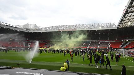 Des supporters de Manchester United en colère contre les propriétaires du club anglais protestent sur la pelouse du stade d'Old Trafford avant la rencontre les Red Devils et Liverpool, dimanche 2 mai 2021. (OLI SCARFF / AFP)