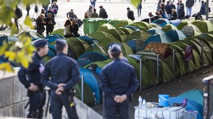 Des policiers observent l'&eacute;vacuation du campement de r&eacute;fugi&eacute;s install&eacute; quai d'Austerlitz &agrave; Paris, le 17 septembre 2015. (GEOFFROY VAN DER HASSELT / ANADOLU AGENCY / AFP)