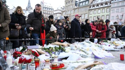 Des passants déposent des fleurs et des bougies sur le mémorial improvisé place Kléber en mémoire des victimes de l'attentat de Strasbourg, le 16 décembre 2018. (SEBASTIEN BOZON / AFP)