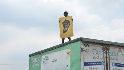 Un manifestant, debout sur un camion, tient une pancarte où il est écrit : "Ne jamais abandonner." Il participe à une manifestation pacifique contre les brutalités policières au Nigeria à Magboro, dans l'Etat d'Ogun, le 20 octobre 2020. (OLUKAYODE JAIYEOLA / NURPHOTO)