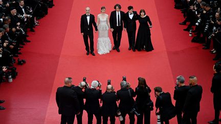 L'équipe du film "The Zone of Interest autour du réalisateur britannique Jonathan Glazer, se laisse photographier, en se tenant les mains. Le long-métrage, en compétition pour la Palme d'Or, raconte le quotidien de l’officier SS Rudolf Höss, installé avec sa famille à côté d'Auschwitz. (ANTONIN THUILLIER / AFP)