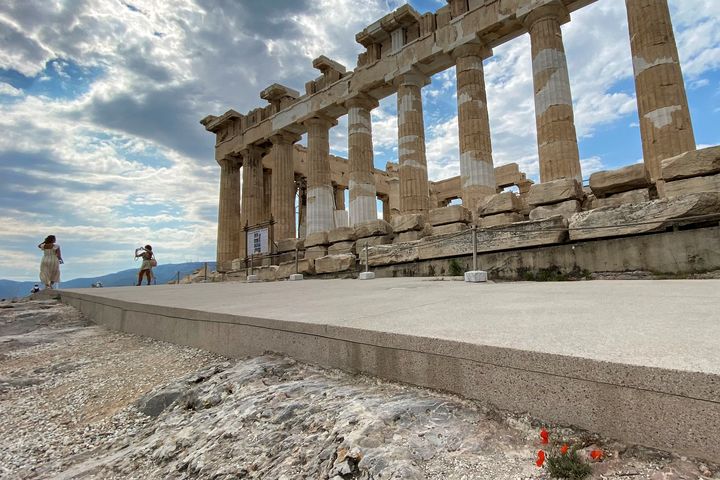 Des touristes prennent des photos devant le temple antique du Parthénon, sur la colline de l'Acropole, après des travaux de réaménagement du site, à Athènes, le 4 juin 2021 (ARIS MESSINIS / AFP)