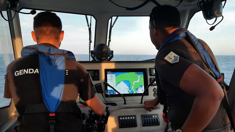 Les gendarmes Ludovic (à gauche) et Mohamedi (à droite), face à l'écran de contrôle du navire de la brigade nautique de Mayotte. (SANDRINE ETOA-ANDEGUE)