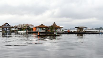 Sur cette photo, prise le 6 août 2019, des pêcheurs passent à côté d'une île artificielle constituée d'environ 700 000 déchets de plastique recyclés, dans la lagune Ebrie à Abidjan. (ISSOUF SANOGO / AFP)