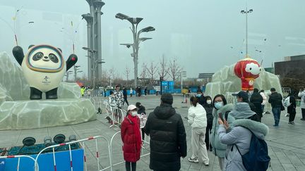 Des Pékinois se&nbsp;prennent en photo devant les mascottes des Jeux olympiques et paralympiques, le 12 février 2022. Cette photo a été prise depuis un des bus de la bulle sanitaire des JO.&nbsp; (Apolline Merle / franceinfo: sport)