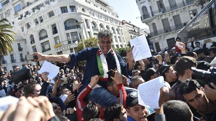 L'homme d'affaires Rachid Nekkaz, candidat déclaré à l'élection présidentielle algérienne, porté par la foule lors d'une manifestation de ses partisans à Alger, le 23 février 2019. (RYAD KRAMDI / AFP)