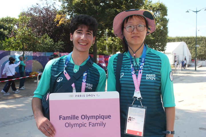 Les bénévoles Adrien et Xingying accueillent les membres de la famille olympique sur le site du Champ-de-Mars, le 29 juillet 2024. (CLEMENT PARROT / FRANCEINFO)