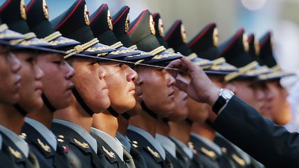 Un officier v&eacute;rifie l'alignement des militaires de la garde d'honneur au moyen d'une cordelette avant le d&eacute;but de la c&eacute;r&eacute;monie de bienvenue au pr&eacute;sident vietnamien &agrave; P&eacute;kin (Chine), le 19 juin 2013. (KIM KYUNG HOON / REUTERS)