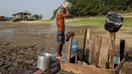 Un homme fait sa toilette avec l'eau issue d'un puits artisanal dans le lac Puraquequara, à sec, à Manaus, au Brésil, le 6 octobre 2023. (MICHAEL DANTAS / AFP)